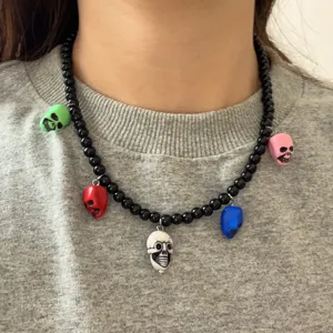 Detail van de zwarte kralenketting met kleurrijke schedelhangers en uniekebedels.