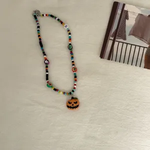 Close-up van Halloween kralenketting met kleurrijke kralen en pompoen hanger detail.