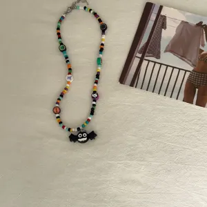 Handgemaakte Halloween kralenketting met zwart vleermuis hanger, kleurrijke sieraden stijl.