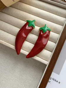Close-up detail of stylish red chili enamel earrings with green stem and gold trim, unique jewelry.