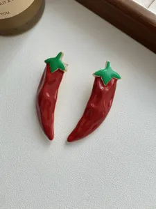 Red chili pepper enamel earrings detail shot showcasing vibrant enamel coating and metallic edge design.