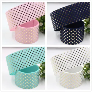 Close-up detail view of 38mm gold polka dot grosgrain ribbon rolls in multiple vibrant colors.