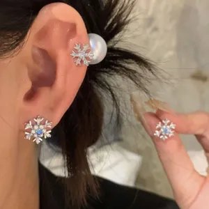 Detailed view of sparkling zircon snowflake earrings with pearl accents worn gracefully.