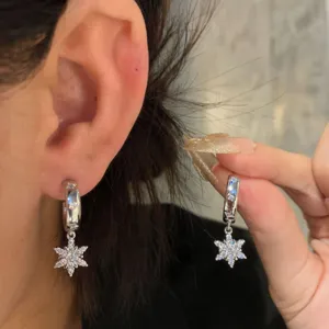 Close-up detail of sparkling zircon snowflake dangle earrings showing crystal brilliance and elegant ear wear.