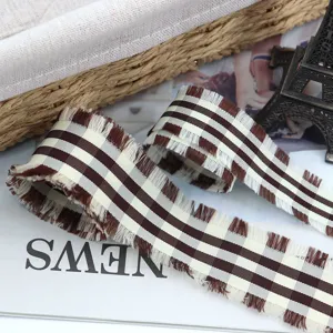 Primo piano di nastro con frange a quadri marrone e bianco, dettaglio materiale fai da te.