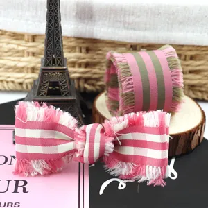 Primo piano del fiocco in nastro con frange a quadri rosa, ideale per accessori fai da te.