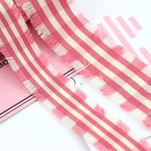 Primo piano nastro a quadri rosa e bianco sfrangiato, dettaglio bordo per fiocchi fatti a mano.