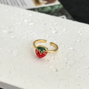 Close-up detail of the gold-plated open ring featuring a cute red and green enamel strawberry.