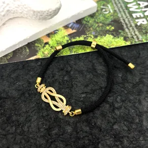 Detailed close-up of a black cord bracelet featuring a gold-toned paved diamond geometric buckle.