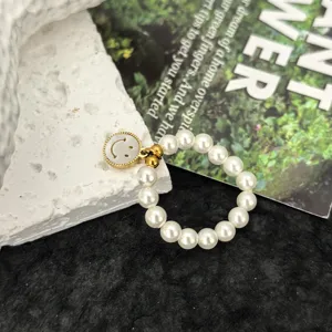 Nahaufnahme des Perl-Smiley-Ring-Details mit elastischem Perlendesign und Anhänger.