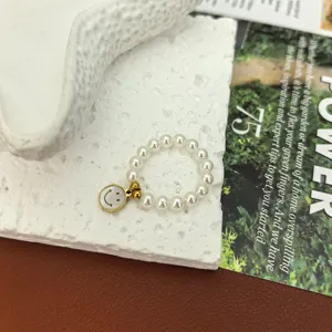 Nahaufnahme eines charmanten elastischen Perlenrings mit einem niedlichen Smiley-Anhänger.