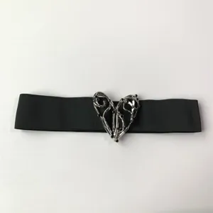 Vista detallada del cinturón elástico negro para mujer con hebilla de corazón plateada.