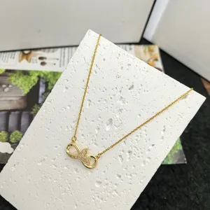 Gold titanium steel infinity necklace detail, shiny cubic zirconia stone pave pendant.