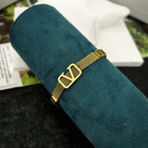 Primo piano di un bracciale in maglia di acciaio inossidabile dorato con logo a V.