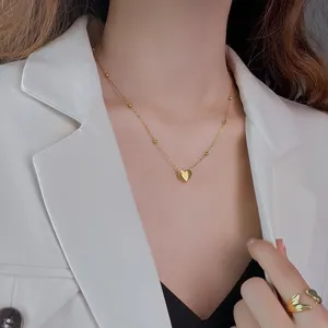 Gros plan détail collier pendentif cœur or délicat sur mannequin, style élégant.