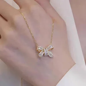 Close-up detail of the sparkling cubic zirconia bow pendant necklace, delicate gold-toned chain.