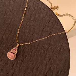 Detail view of a gold-tone chain necklace featuring a pink hulu pendant with sparkling accents.
