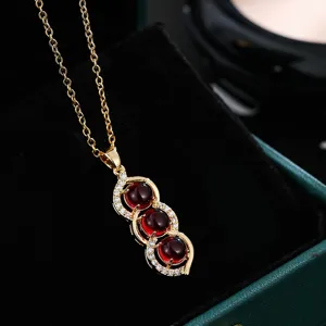 Delicate gold-tone peapod pendant necklace with three red stones and sparkling cubic zirconia.