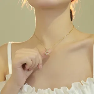 Close-up detail of a delicate gold-toned clavicle necklace featuring a sparkling crystal pendant.