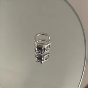 Detailed close-up view of silver-tone ear cuff with purple square zircon on mirror.