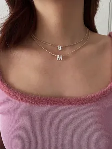 Nahaufnahme Detail der doppelten Perlen Perlmutt Buchstaben Halskette am Hals getragen.