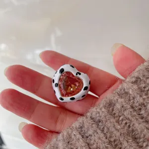 Detail shot of a chic heart-shaped pink crystal ring with cute black and white cow print enamel.