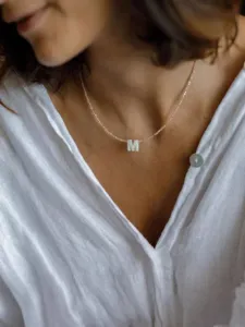Detailansicht einer zarten handgemachten Perlenkette mit einem eleganten Muschel-Buchstaben.