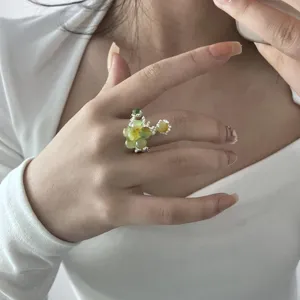 Hand detail shot of niche design green stone beaded ring with silver molten open band style.