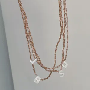 Detailansicht der mehrsträngigen Perlenkette mit eleganten Muschelbuchstaben-Anhängern.