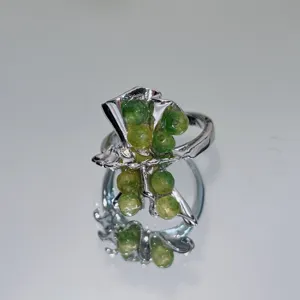 Close-up view of the handmade green stone beaded silver ring with unique molten design.