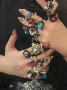 Detailed close-up showing multiple vintage beaded and button stackable rings worn on fingers.