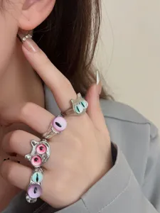 Close-up detail of trendy stackable open rings with cute monster cat eye designs for women.
