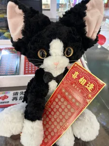 Cute black and white curly cat plush toy doll with a bow tie, detailed closeup.