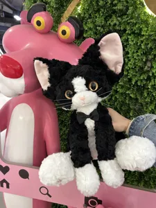 Detailed view of the black and white curly cat plush toy, soft texture and cute bow tie.