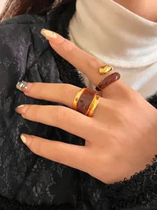 Close-up shot of a stylish double-layer metal and chocolate enamel open ring on hand.