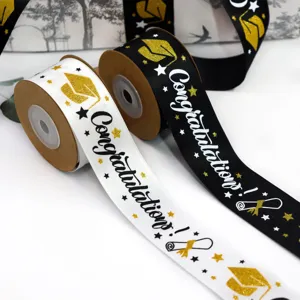 Close-up detail of black and white graduation ribbon with gold glitter cap pattern.