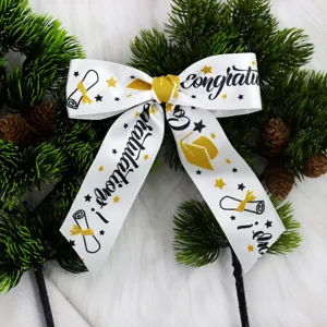 Graduation themed white ribbon detail shot with black and gold glitter congratulations print.