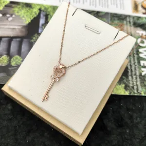 Rose gold key pendant necklace with sparkling cubic zirconia, elegant clavicle chain jewelry.
