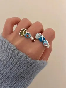 Close-up of handmade wire-wrapped beaded rings, featuring colorful stones and fine metal.