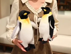 Close up view of cute plush penguin toys held by hands, soft stuffed animal doll details.
