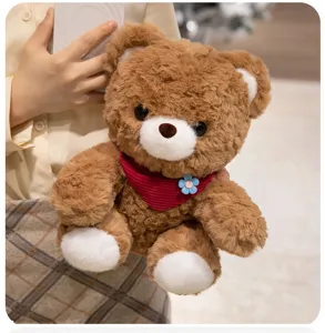 Cute brown plush bear detail showing soft fluffy fabric texture and lovely red scarf decoration.