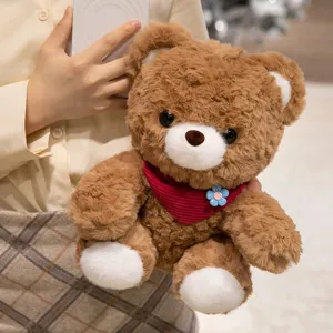 Cute brown plush teddy bear toy with red scarf and flower, soft huggable stuffed animal doll.