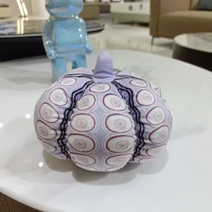 Vue detaillee de la peluche citrouille violette avec des motifs circulaires uniques sur la table.