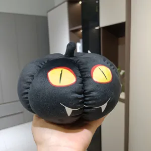 Détail peluche citrouille noire Halloween, poupée tissu avec yeux chat et crocs de vampire.