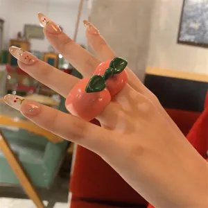Close-up detail van een schattige dikke fruitring gedragen aan vinger, stijlvol zoet cool accessoire.