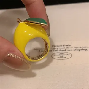 Detailopname van een gele citroen geëmailleerde ring met groen blad, modieuze vingerring.