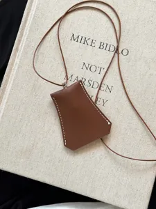 Detail shot of the brown leather sunglasses pouch necklace, portable lanyard storage accessory.