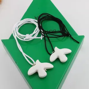 Ceramic dove pendant necklaces with black and white braided rope cords, detail view.