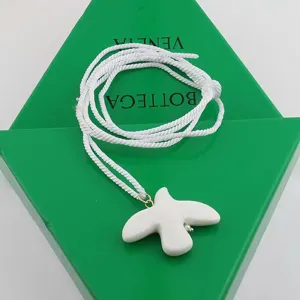 White ceramic dove pendant necklace with white woven rope, elegant long sweater chain accessory.