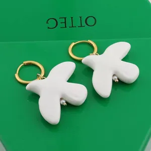 White ceramic peace dove earrings with gold hoop and pearl detail, elegant chic fashion jewelry.